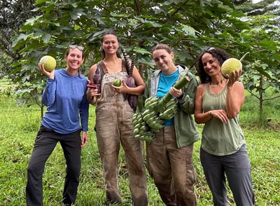 4 women holding harvested fruits